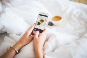 Taking a photo of a latte in bed on an iPhone.